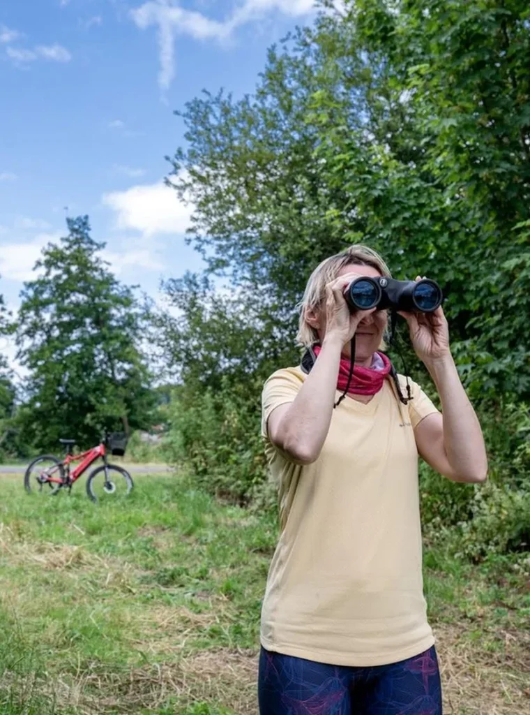 Une femme cycliste en observation des stands à Saint-Aubin-le-Cauf, avec des jumelles
