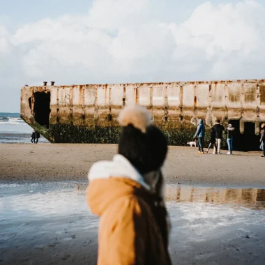 Un enfant en hiver devant une barque du port artificiel d'Arromanches