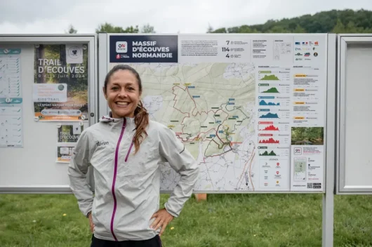 Sylvaine Cussot devant le panneau de la station de trail du Massif d'Ecouves