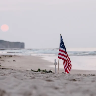 Drapeau américain sur la plage d'Omaha Beach au soleil couchant