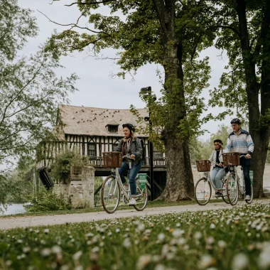 Trois personnes à vélo devant le Vieux Moulin de Vernon