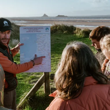 Homme montrant une carte à un groupe en baie du Mont-Saint-Michel à l'occasion de l'expérience Birding