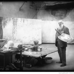 Photo ancienne de Claude Monet, peintre, dans son atelier, avec une palette à la main et ses oeuvres
