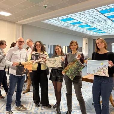 Des collaborateurs de Normandie Tourisme présentant les pochettes ordinateurs recyclées